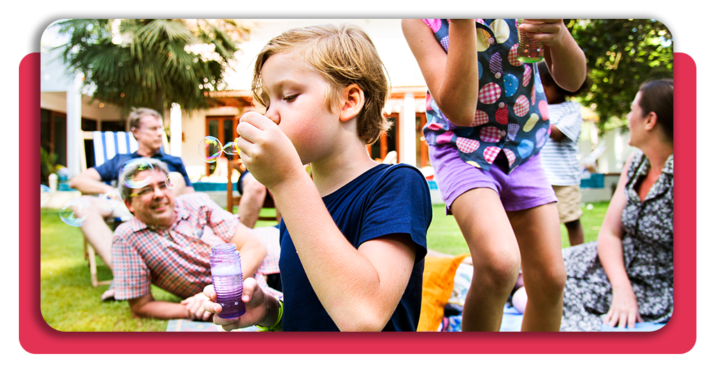 Capacítate en dinámicas grupales y actividades para niños y jóvenes 3 Menores participando en dinámicas para menores de edad con burbujas gigantes al aire libre, guiados por monitores especializados en España