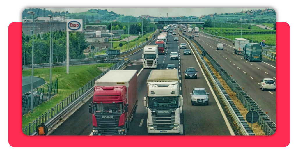 Organización del transporte y la distribución: formación gratuita 2 Varios camiones de transporte de mercancía circulan libremente por una autopista durante el día. En los demás carriles hay vehículos pequeños.