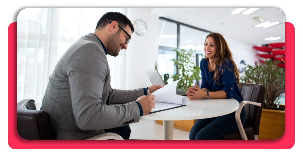 Un hombre firma un contrato luego de haber conversado con una mujer sobre el tipo de trabajo a realizar en una empresa. Ambos parecen estar satisfechos.
